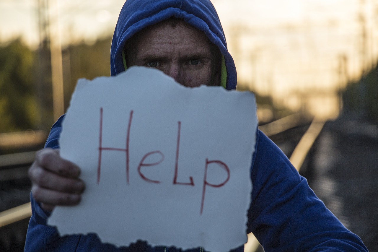 mężczyzna trzymający kartkę z napisem HELP