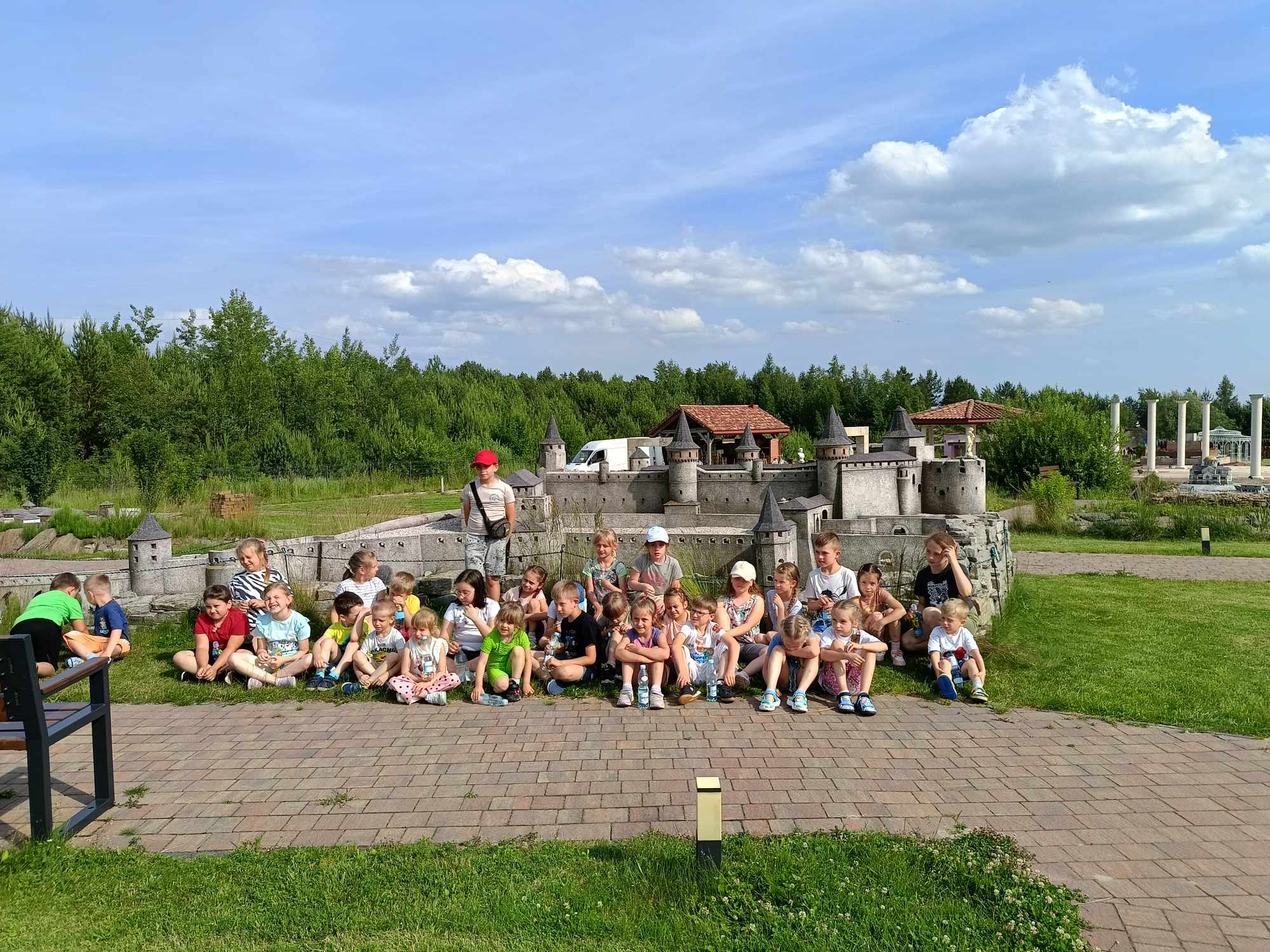 Przedszkolaki i uczniowie pierwszej klasy z opiekunami na tle miniatury zamku