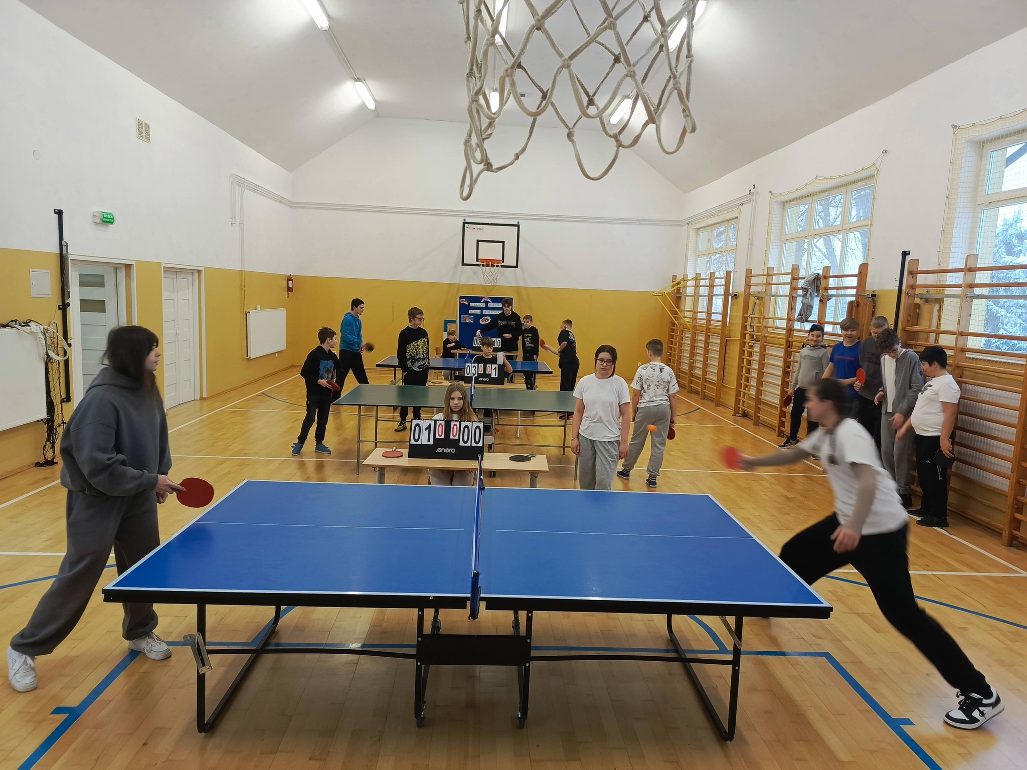 Uczniowie rozgrywają mecze tenisa stołowego w sali gimnastycznej