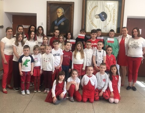 Grupa uczniów z nauczycielami - wszyscy ubrani w stroje w kolorach flagi Polski