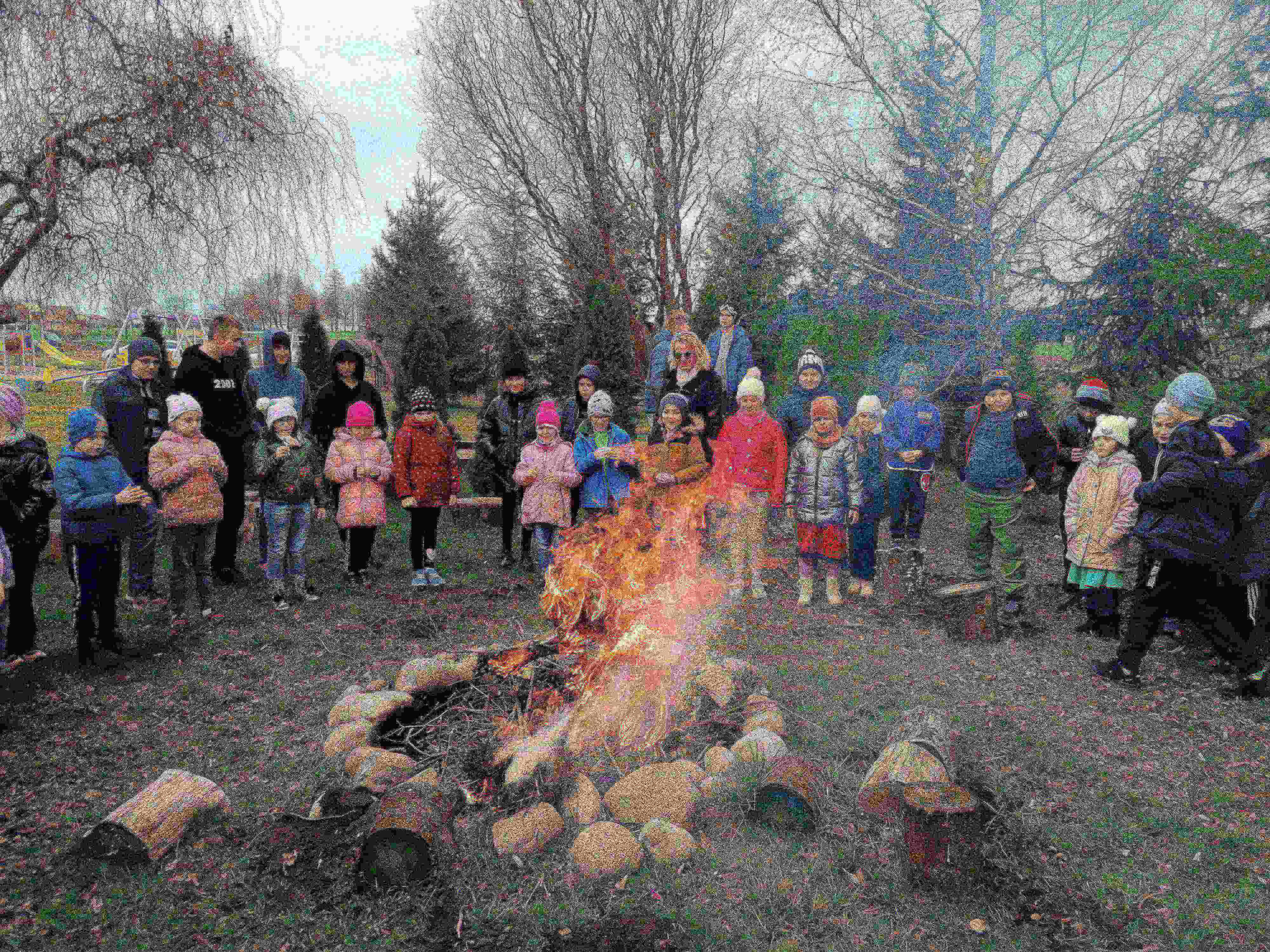 Uczniowie stoją wokół ogniska, w którym pali się Marzanna