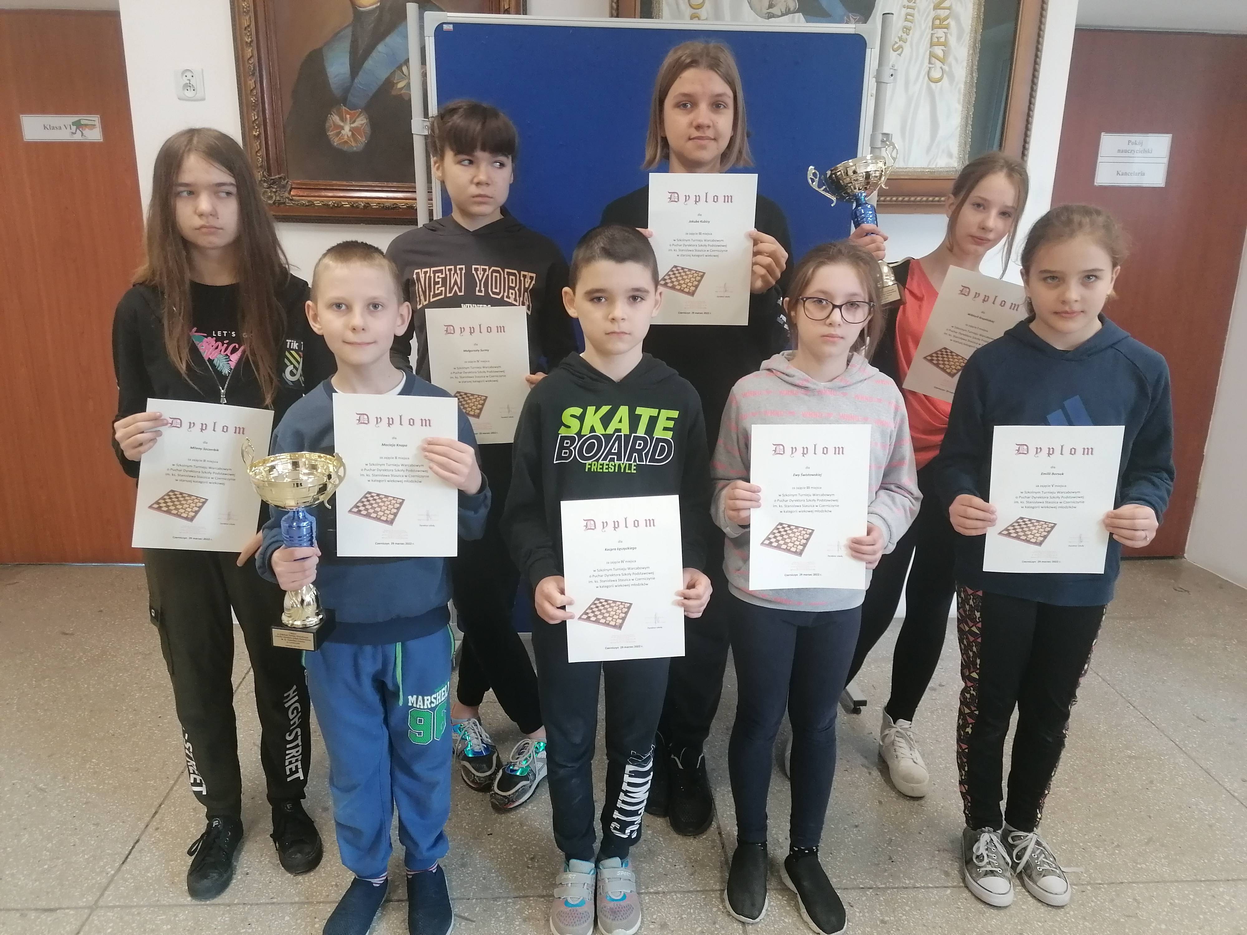 Chłopcy i dziewczęta - uczniowie klas I-VIII - prezentują dyplomy zdobyte w turnieju warcabowym