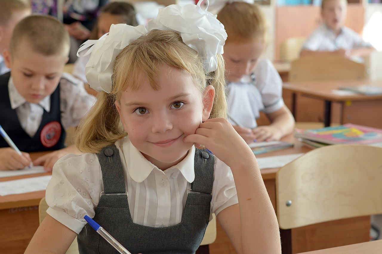 Uśmiechnięta uczennica z białą kokardką na głowie