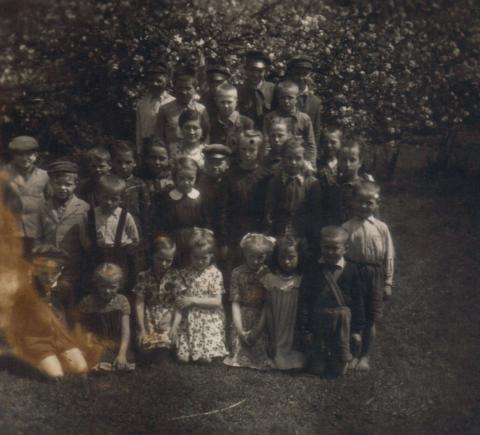 Stare zdjęcie, czarno-białe, grupa dzieci w różnym wieku, w tle sad jabłoni