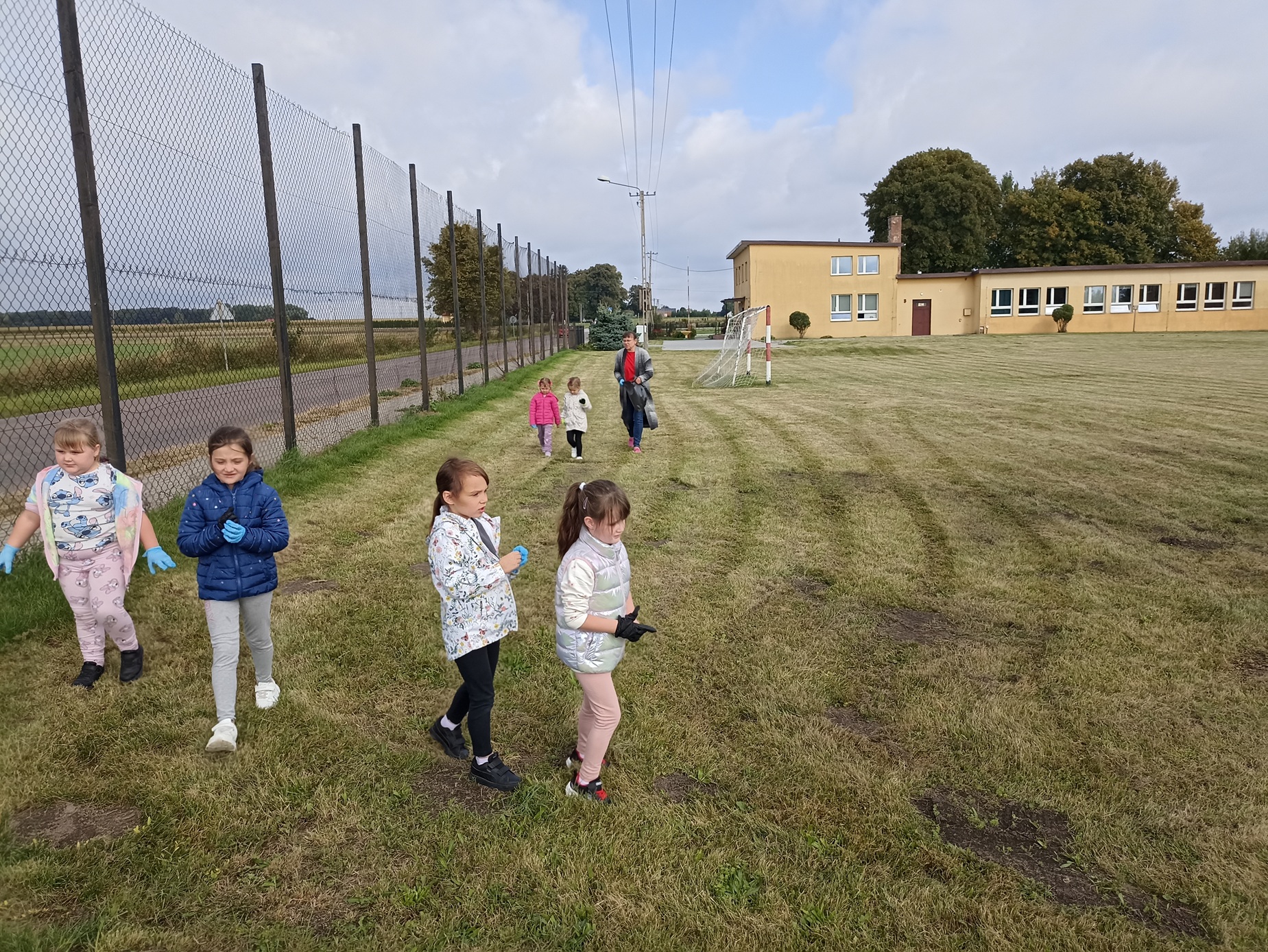 Dzieci z zerówki porządkują teren szkoły.
