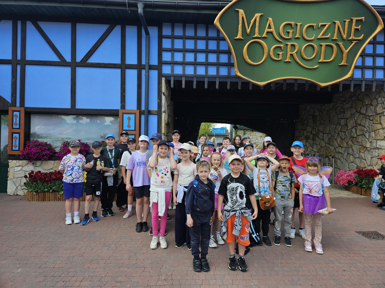 Uczniowie klas I–V pozują do wspólnego zdjęcia przed wejściem do Magicznych Ogrodów.