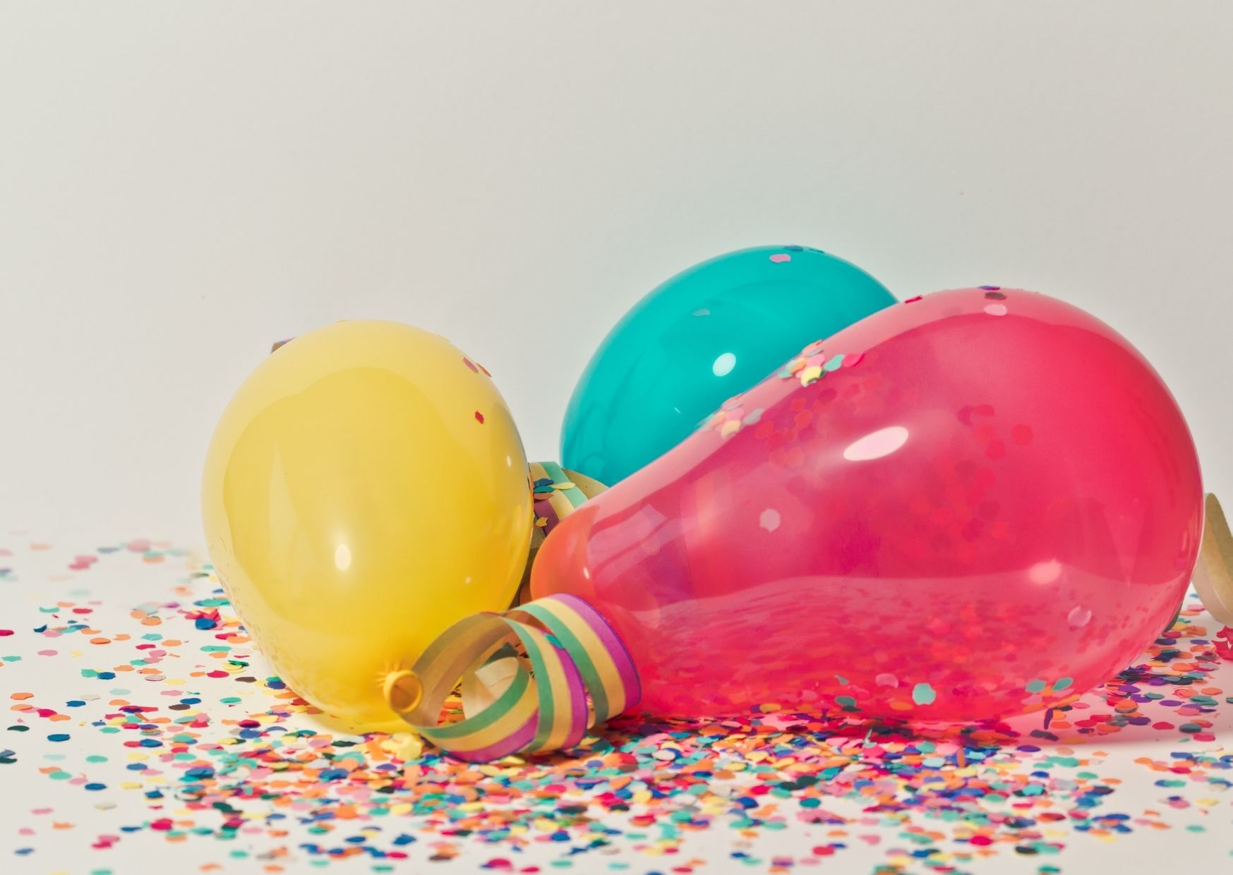 Kolorowe balony, serpentyny i konfetti, leżą na podłodze.