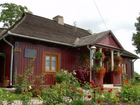Czerwony, drewniany budynek pokryty dachówką