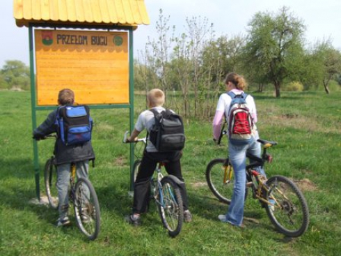 trzech rowerzystów przy tablicy informacyjnej