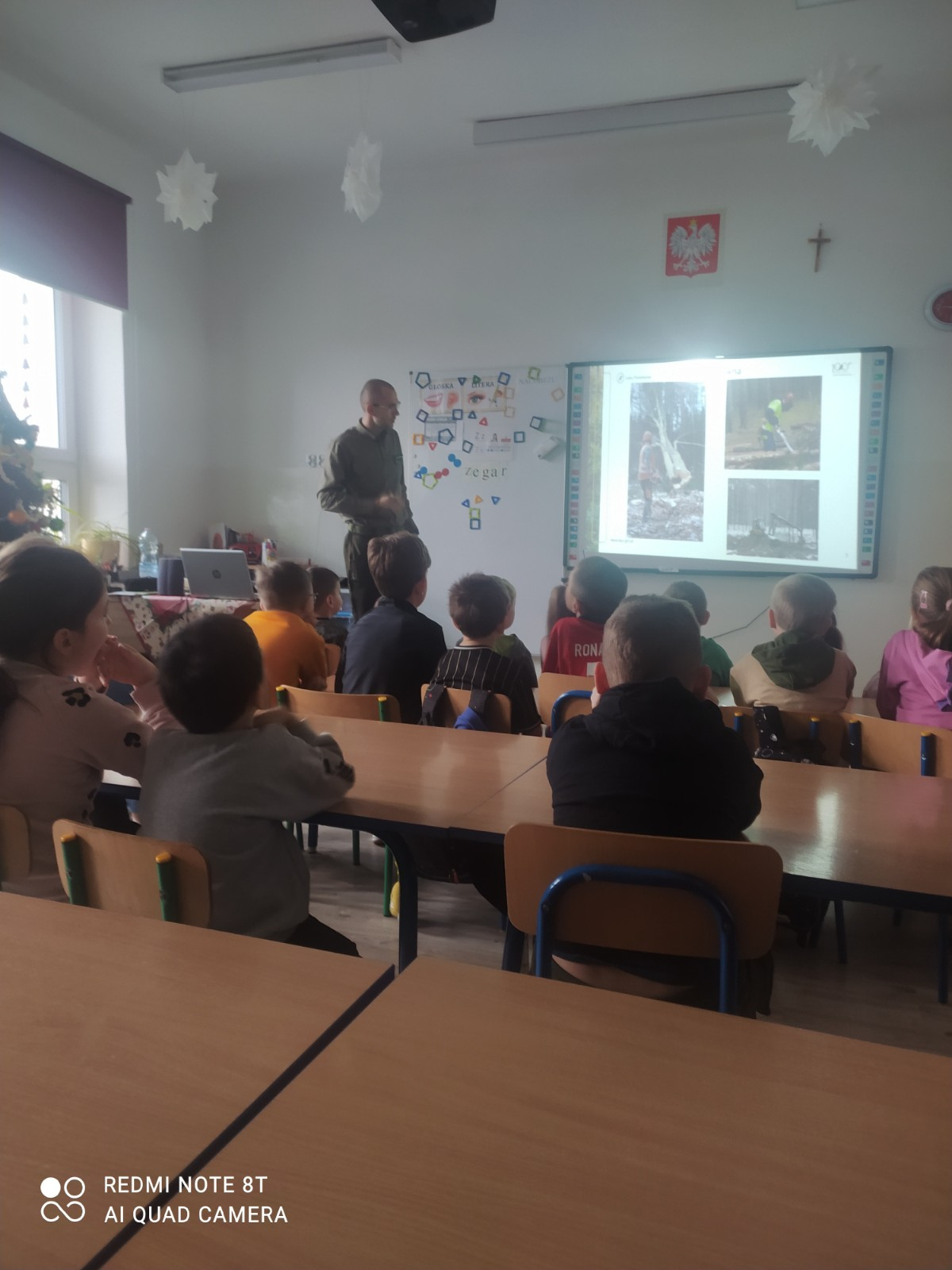 Dzieci i uczniowie oglądają prezentację przygotowaną przez leśnika.