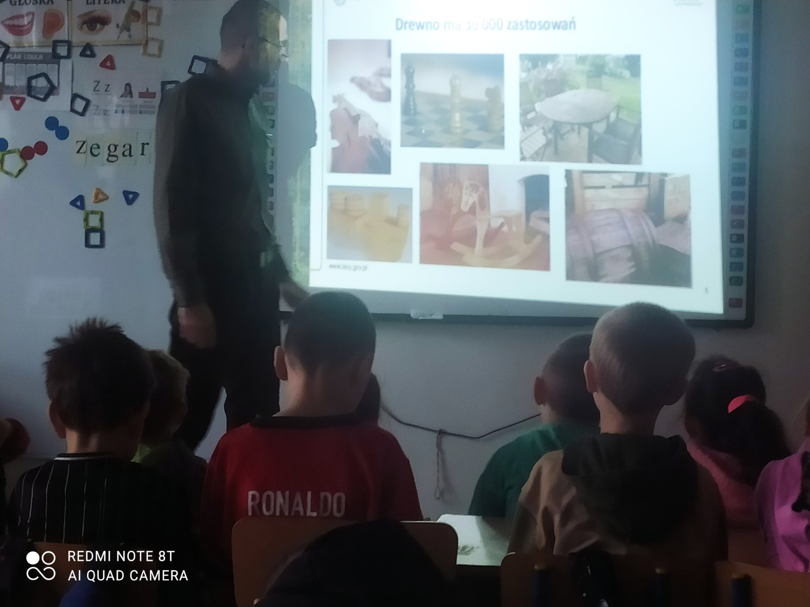 Dzieci i uczniowie oglądają prezentację przygotowaną przez leśnika.