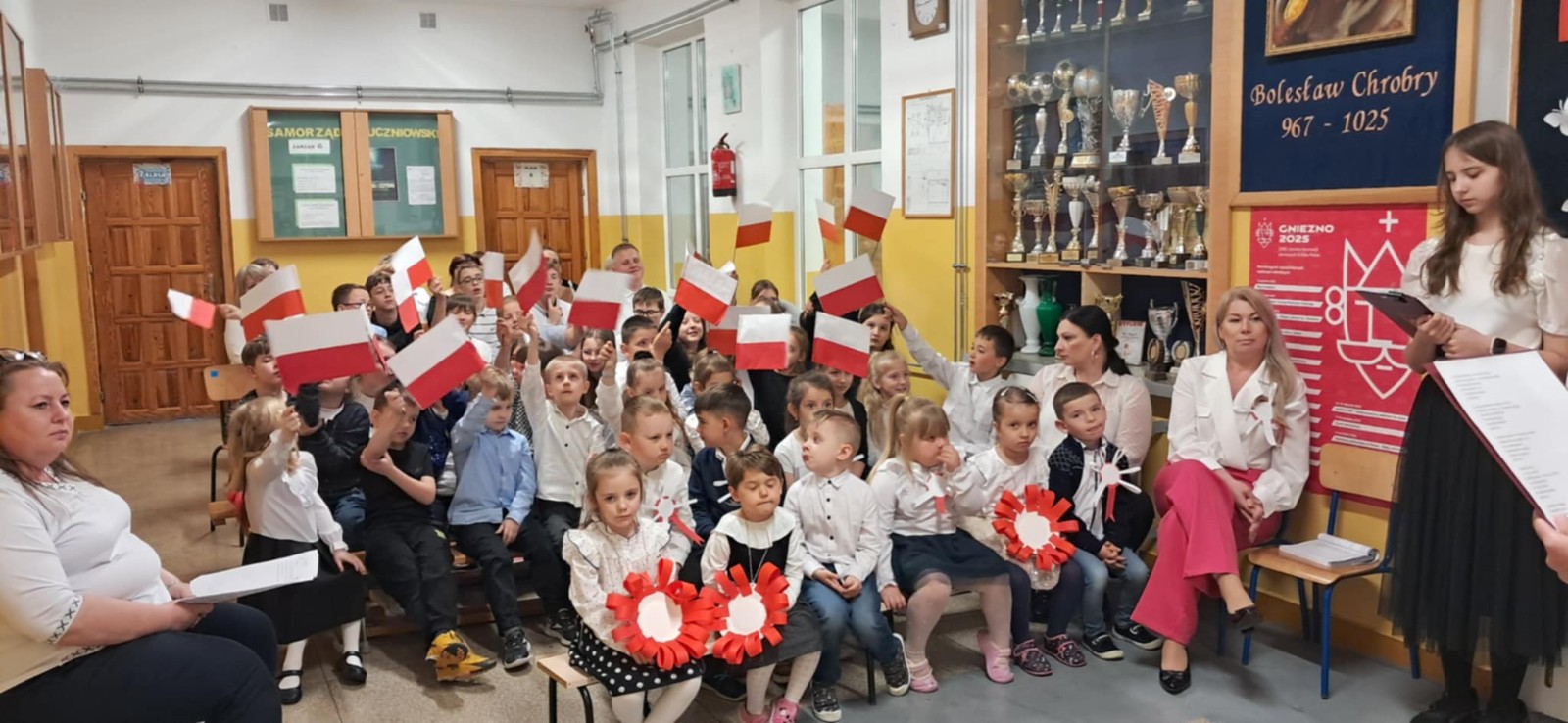 Dzieci wraz z uczniami szkoły podstawowej oraz nauczycielkami wysłuchują przygotowanej akademii.