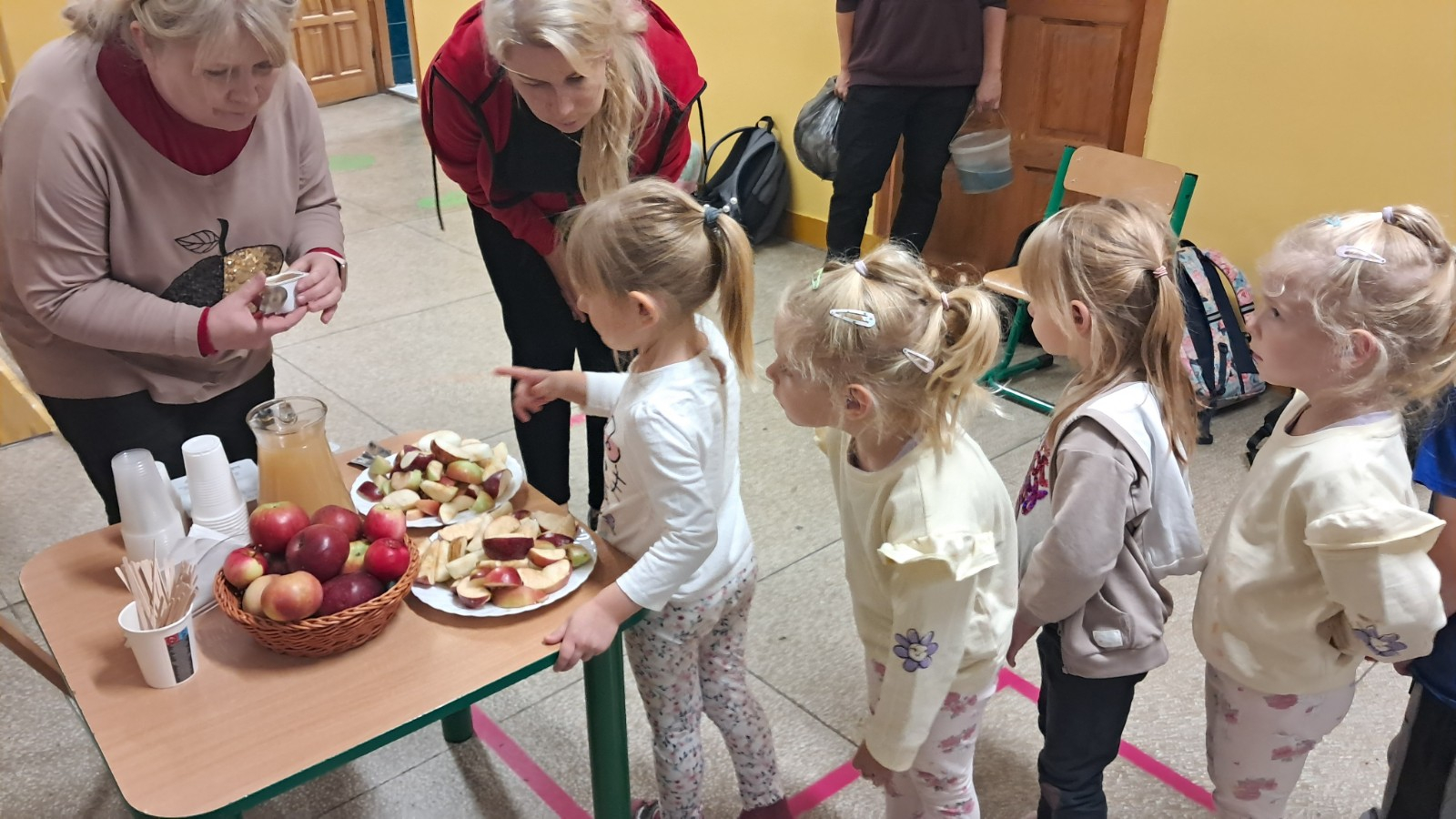 Dzieci degustują jabłka i sok z jabłek.
