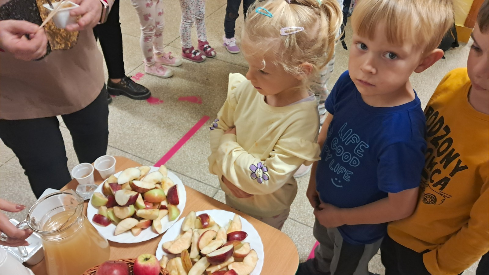 Dzieci degustują jabłka i sok z jabłek.