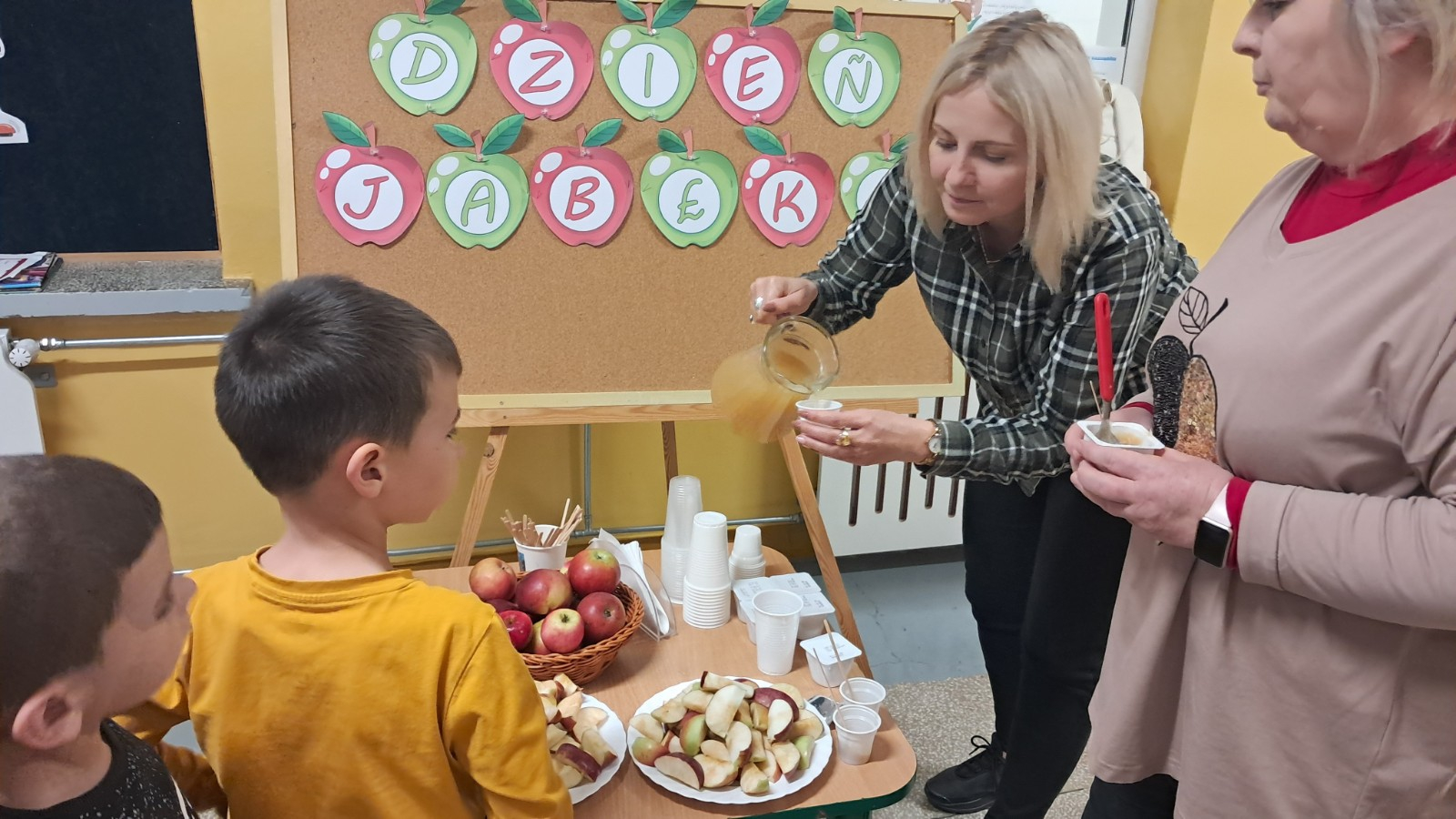 Dzieci degustują jabłka i sok z jabłek.