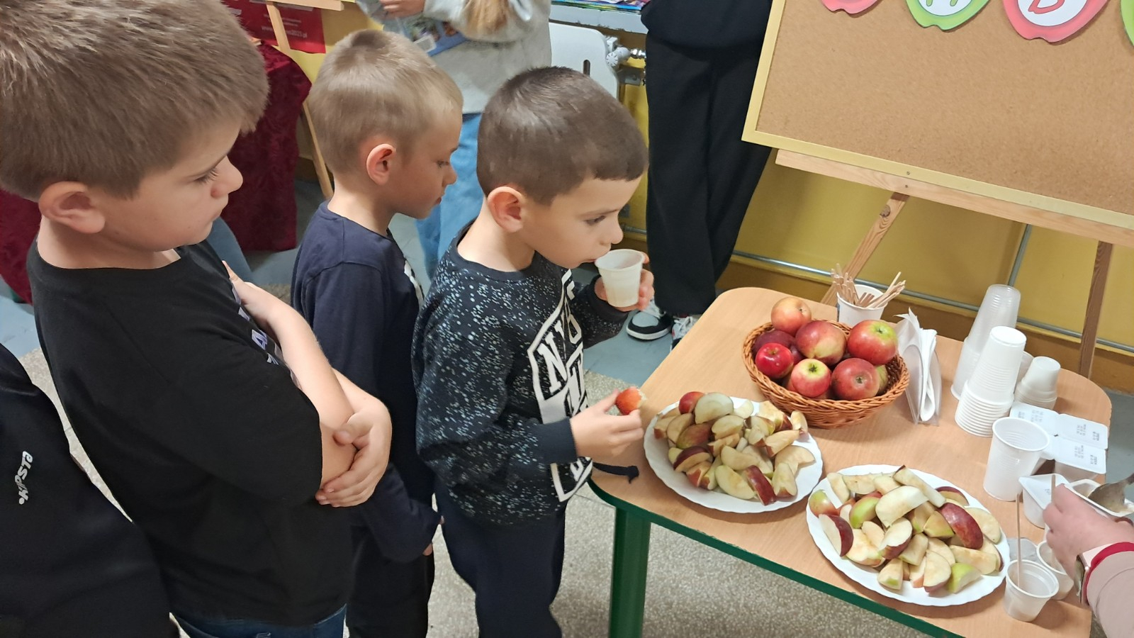 Dzieci degustują jabłka i sok z jabłek.