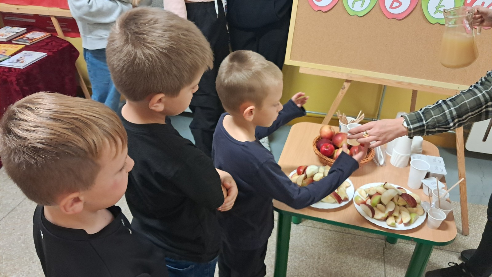 Dzieci degustują jabłka i sok z jabłek.