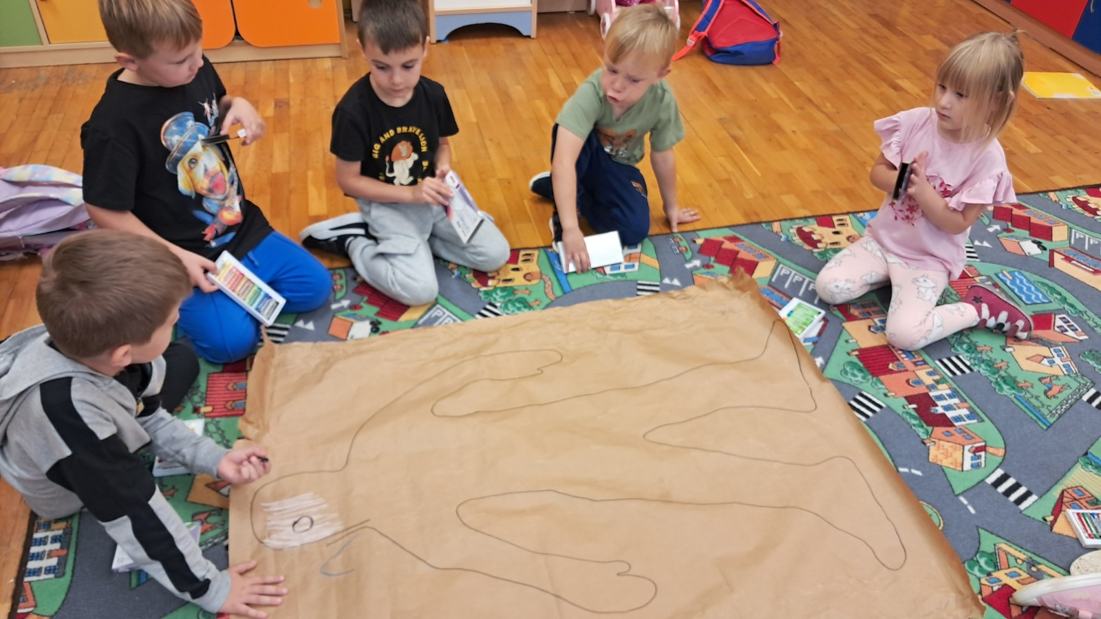 Dzieci odrysowują postać chłopca, a potem kolorują.