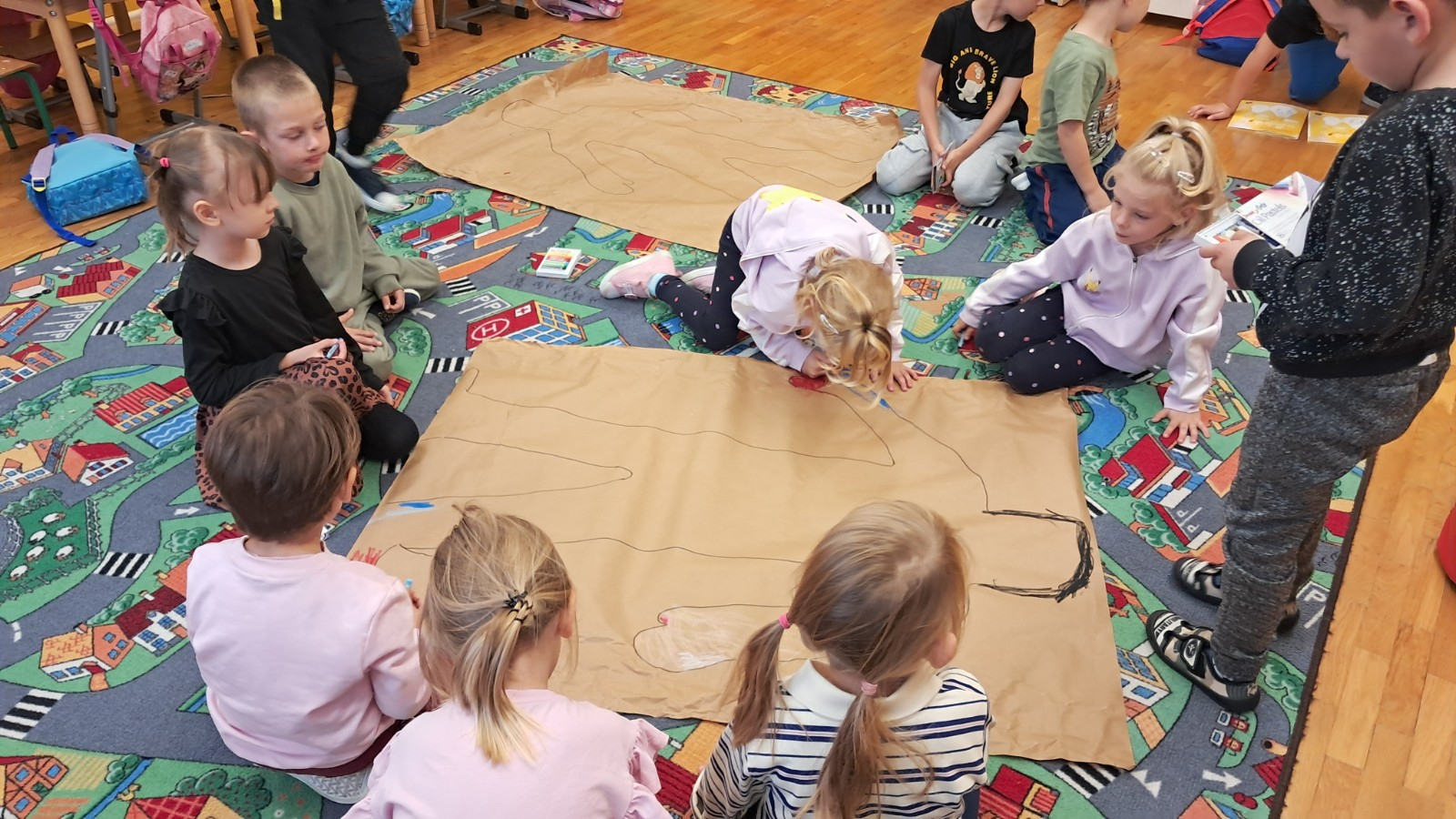 Dzieci rysują na dużym arkuszu papieru.