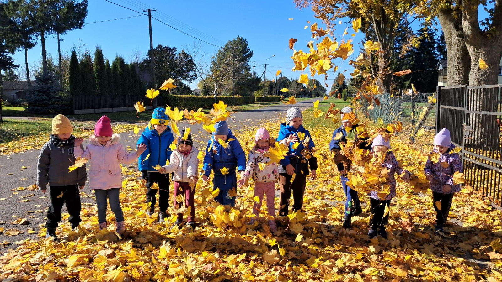 Dzieci prezentują się w tle jesiennych liści.
