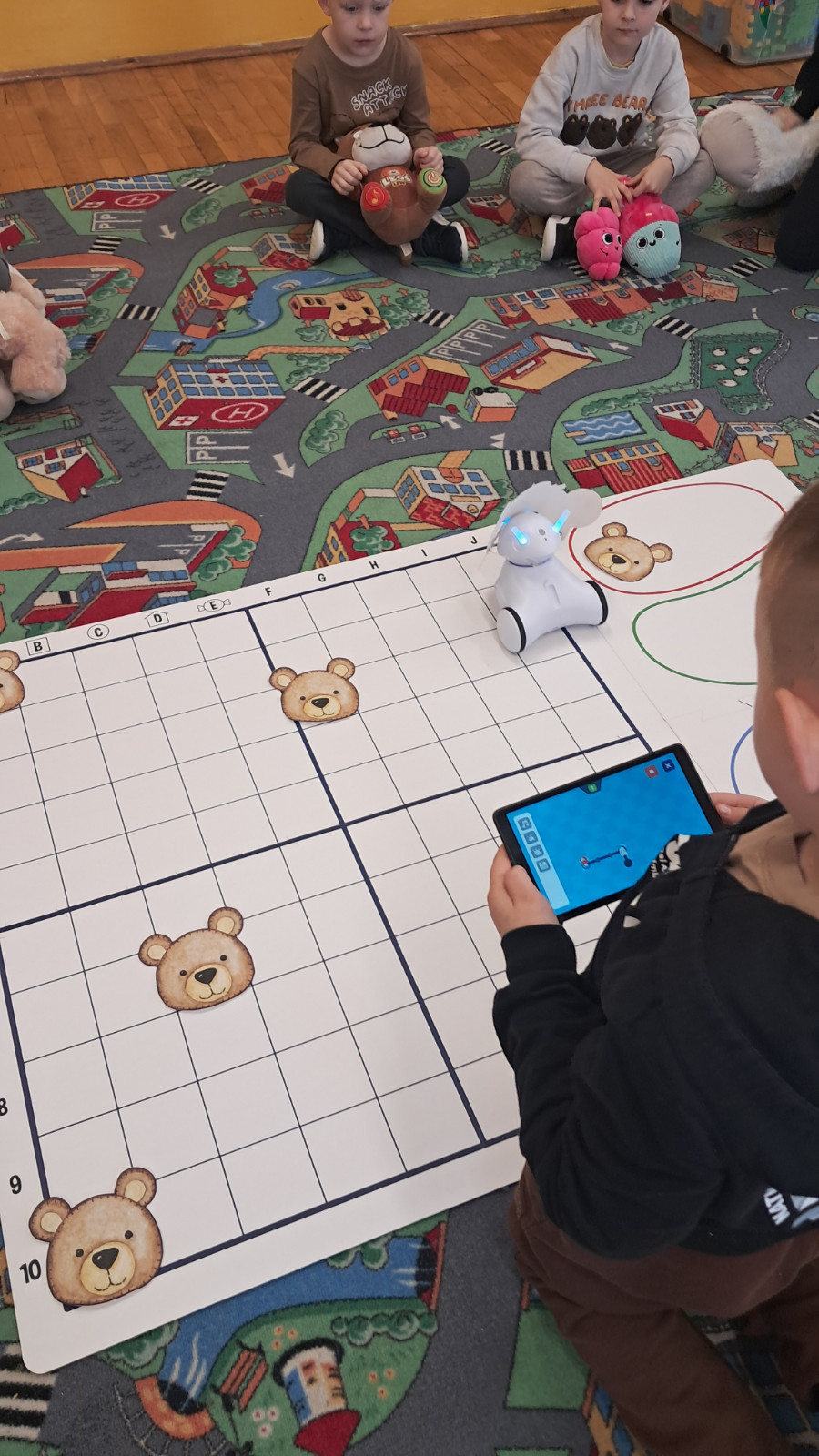 Dzieci biorą udział w kodowaniu na dywanie.