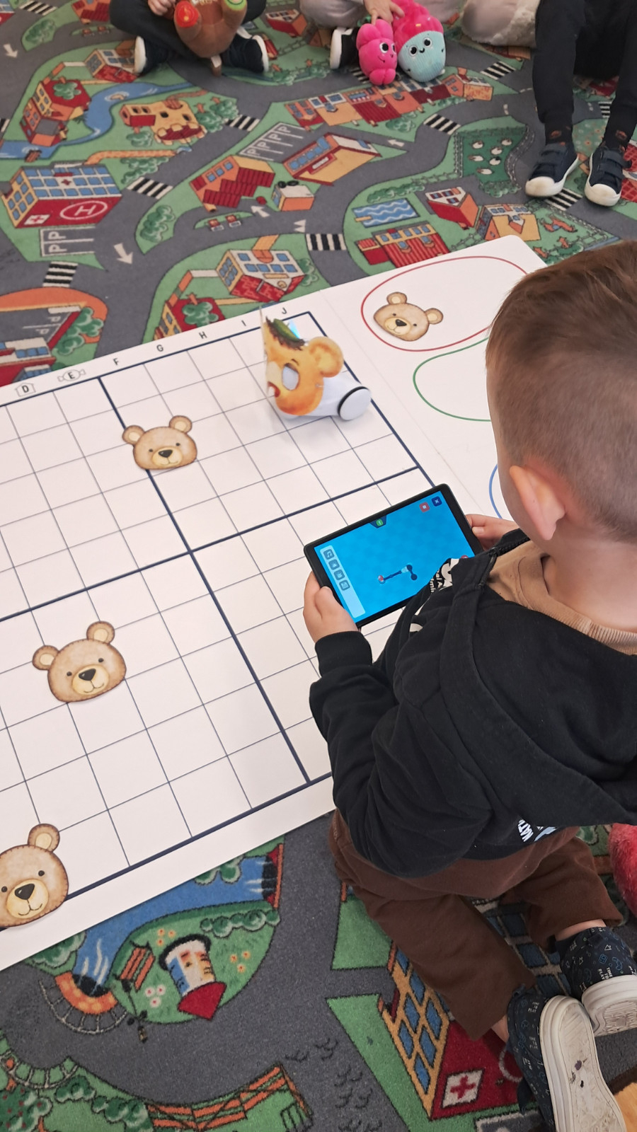 Dzieci biorą udział w kodowaniu na dywanie.