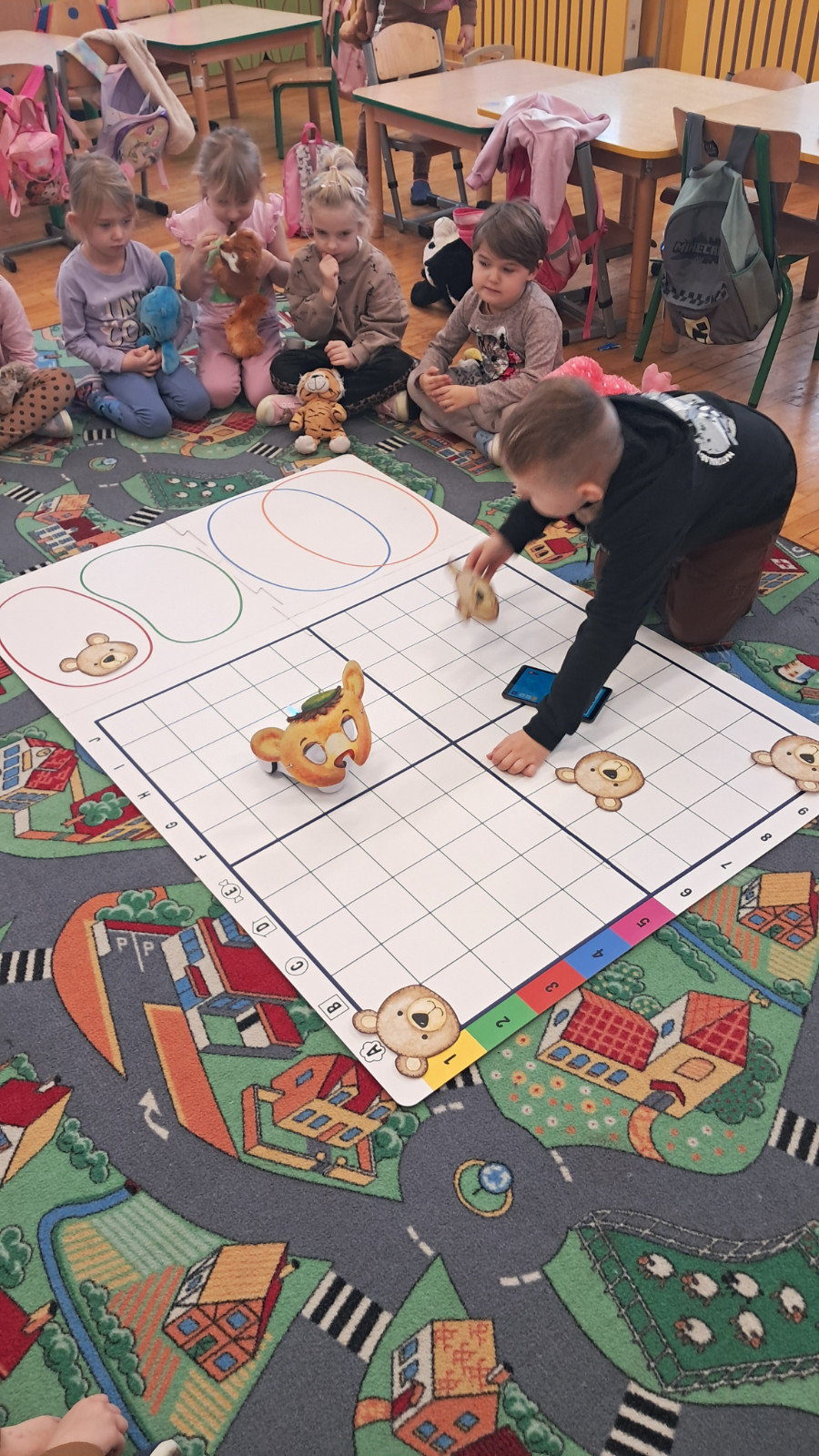 Dzieci biorą udział w kodowaniu na dywanie.