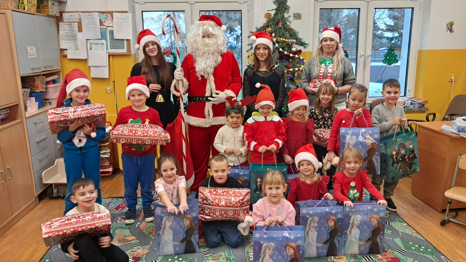 Dzieci prezentują się do zdjęcia z Mikołajem i jego pomocnicami.