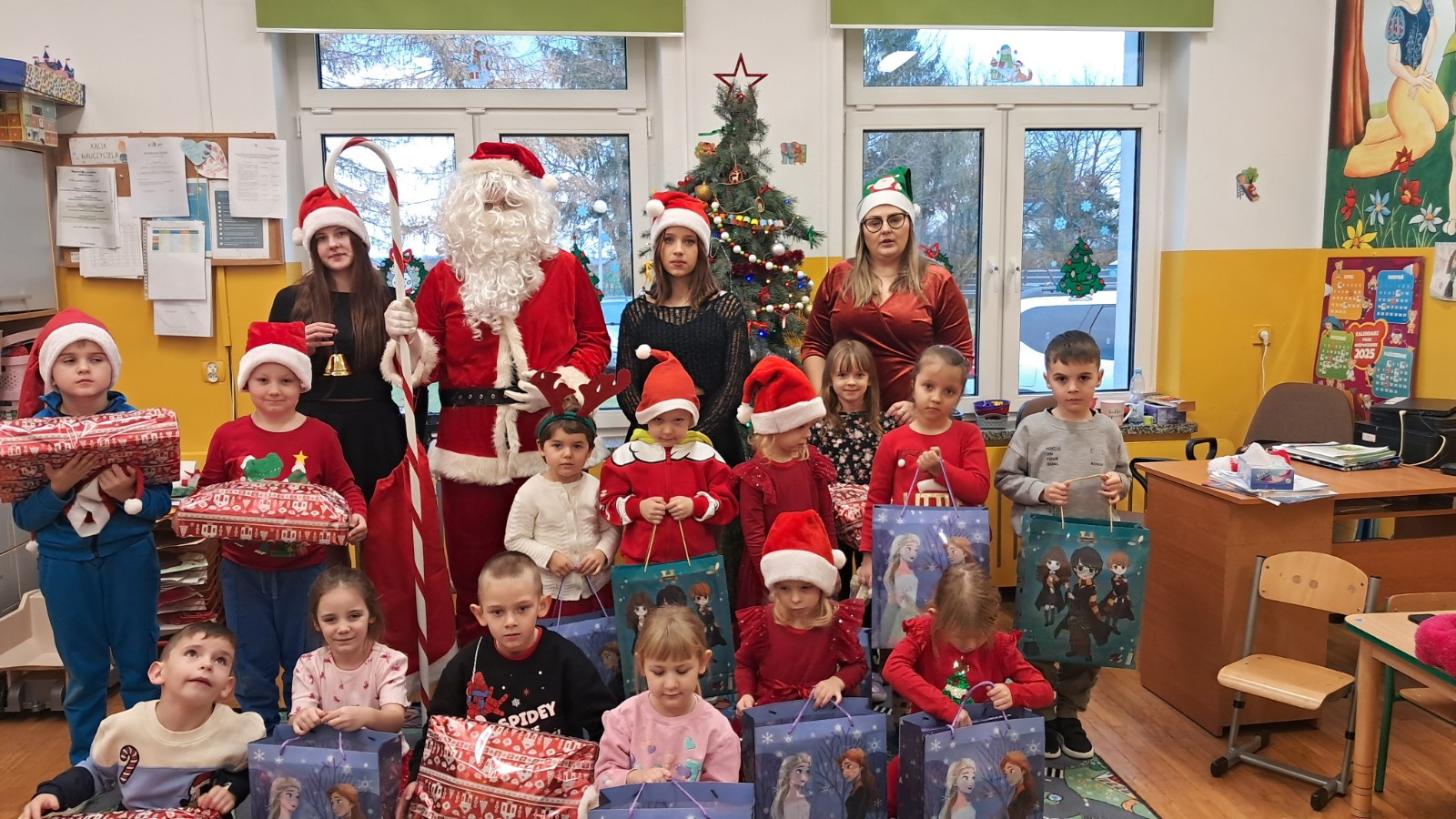 Dzieci prezentują się do zdjęcia z Mikołajem i jego pomocnicami.