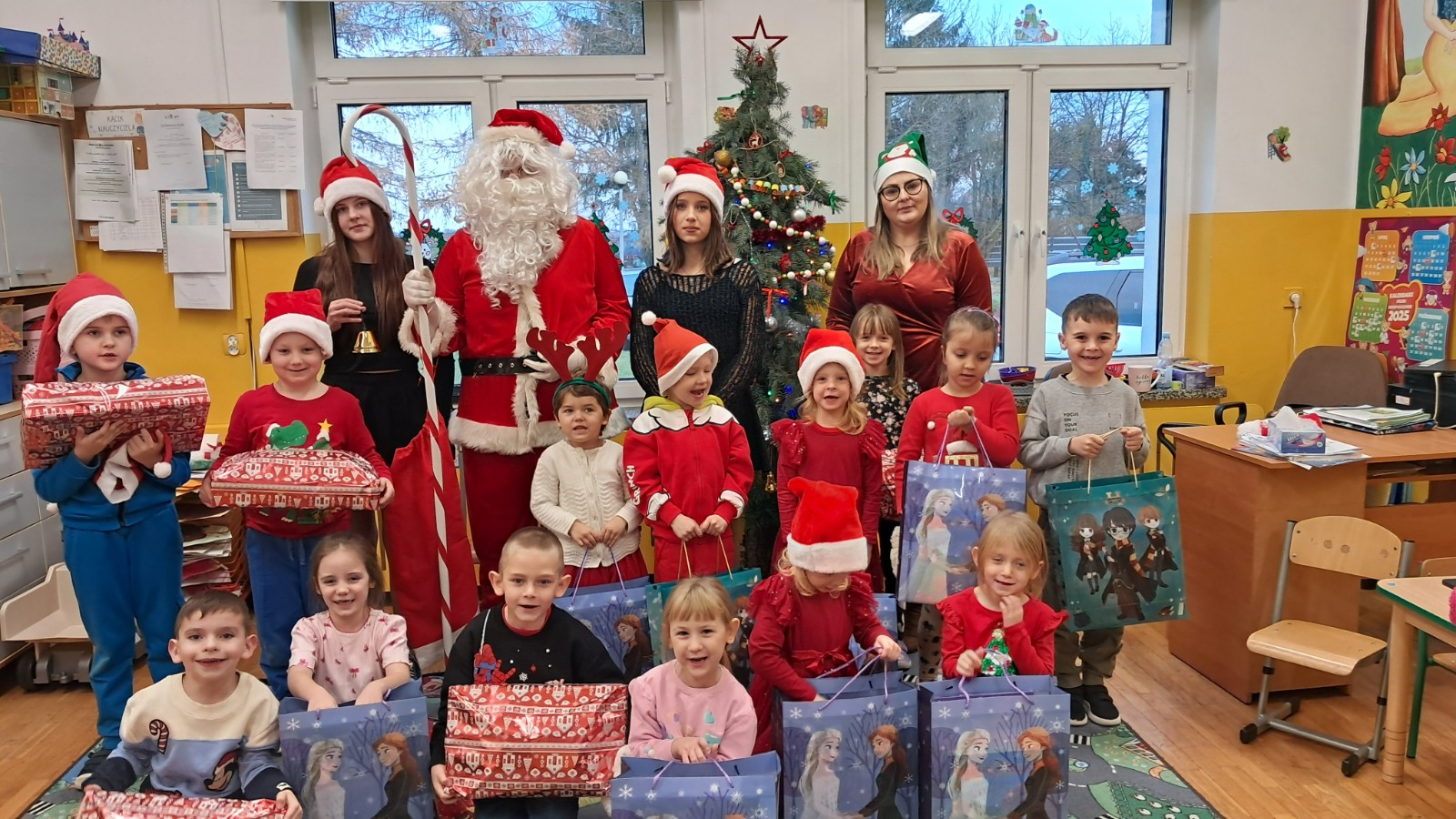 Dzieci prezentują się do zdjęcia z Mikołajem i jego pomocnicami.