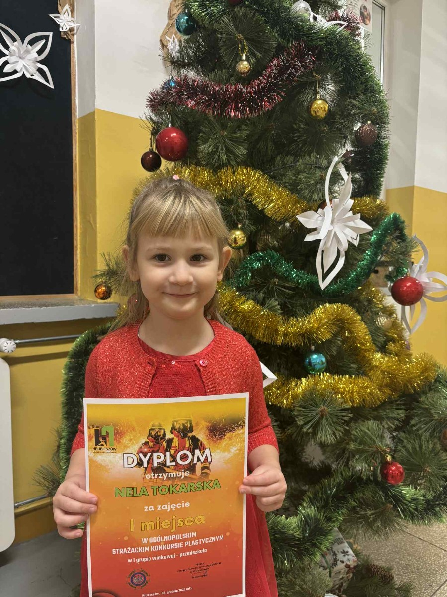 Dziewczynka pozuje do zdjęcia z dyplomem.