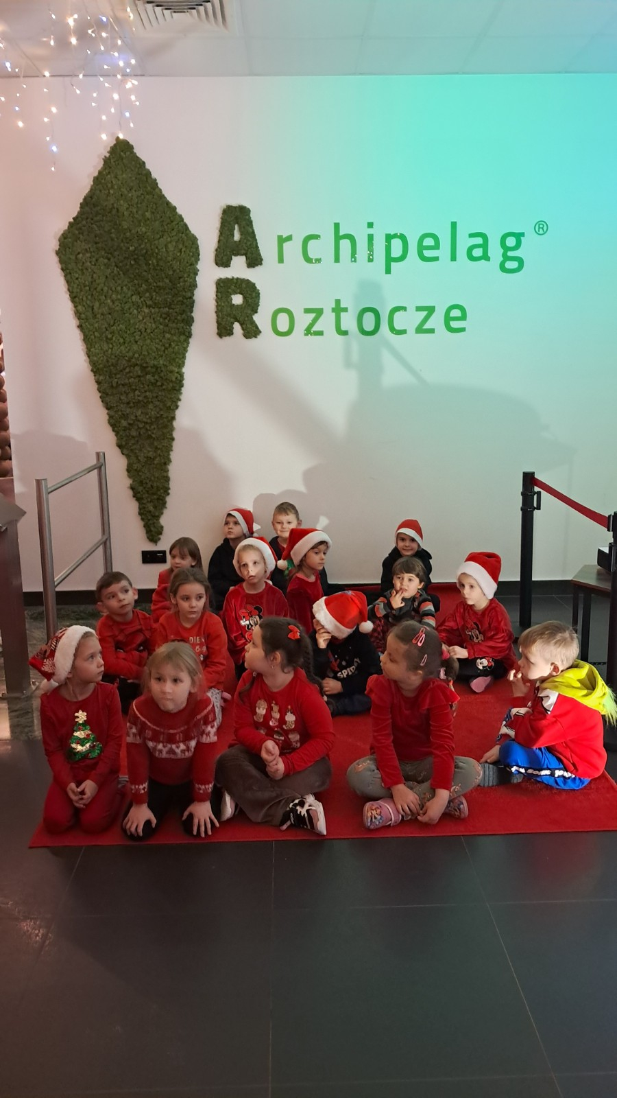 Dzieci pozują do zdjęcia w świątecznej scenerii.