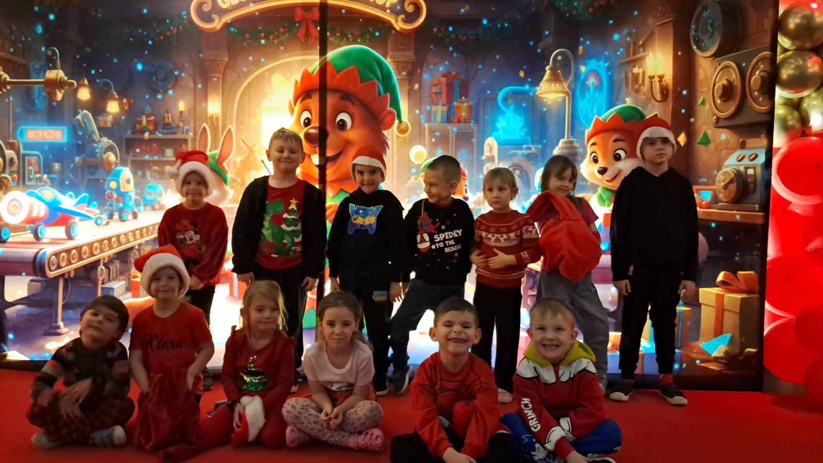 Dzieci pozują do zdjęcia w świątecznej scenerii.