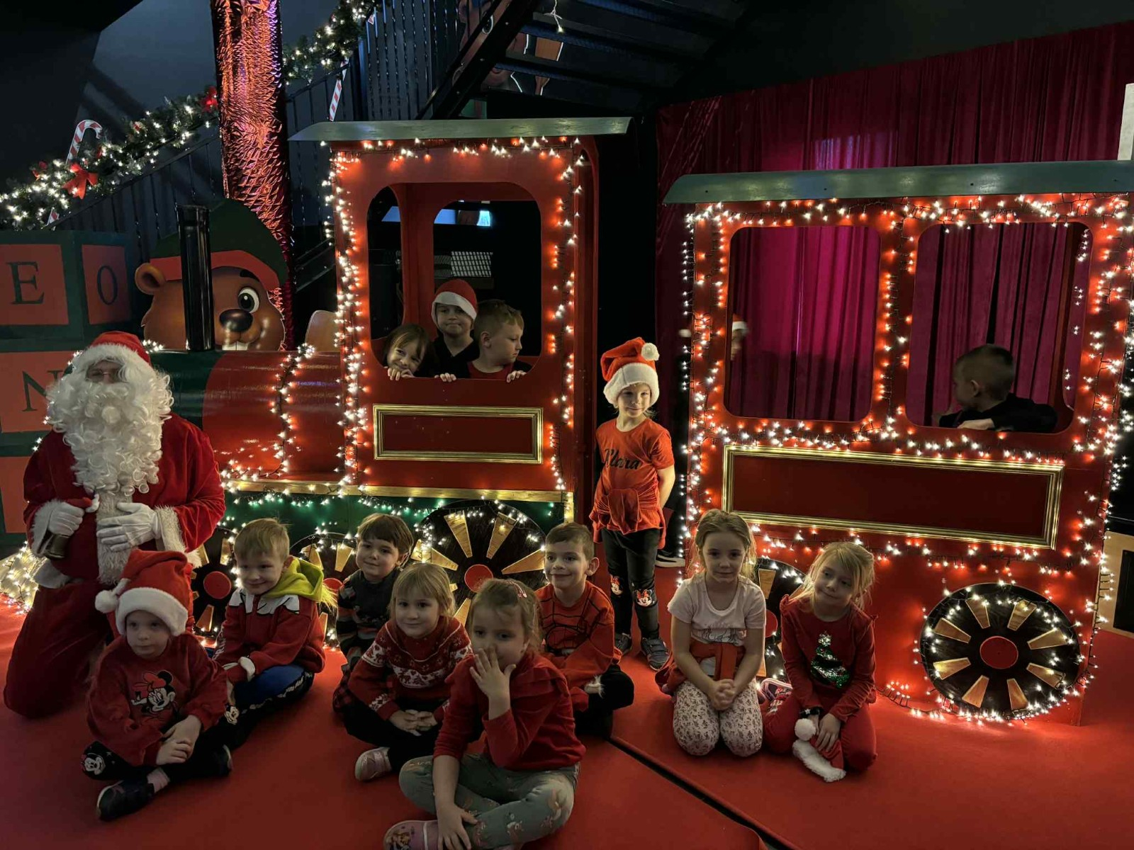 Dzieci pozują do zdjęcia w świątecznej scenerii.