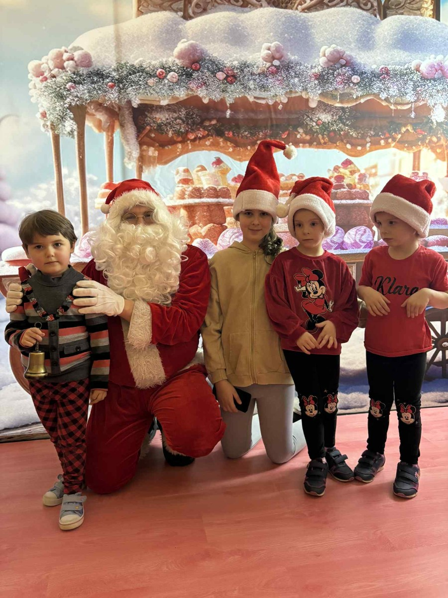 Dzieci pozują do zdjęcia w świątecznej scenerii.