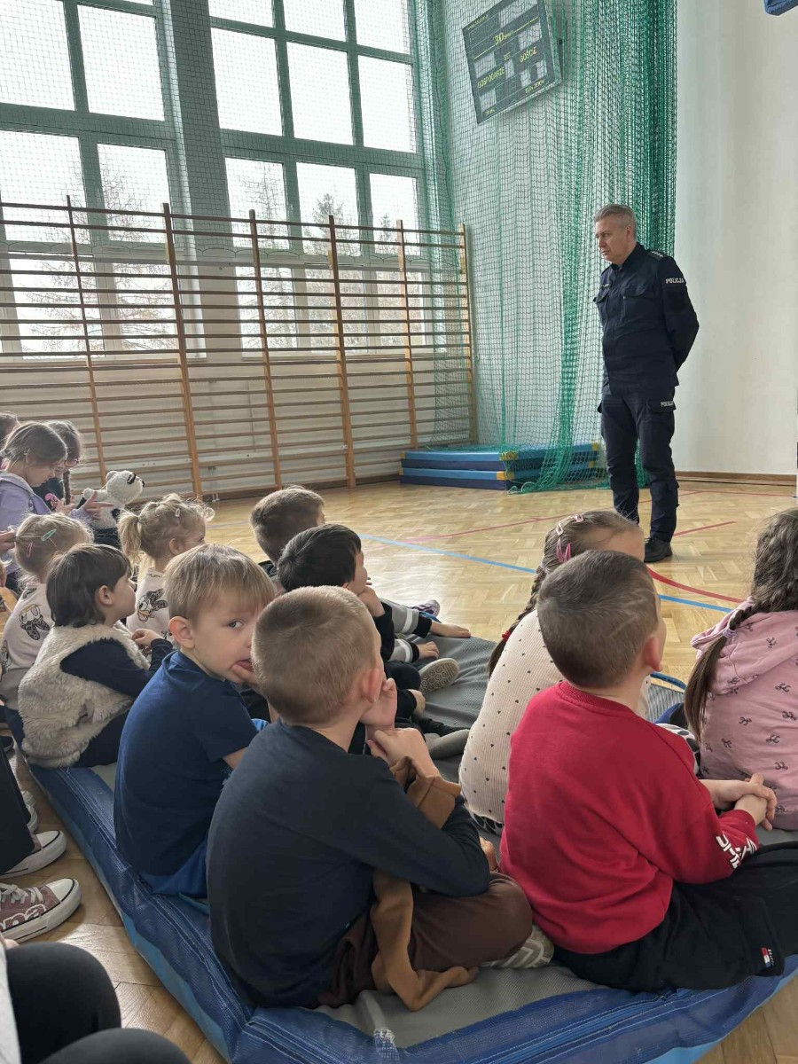 Policjant przekazuje społeczności szkolnej informacje na temat bezpieczeństwa podczas jazdy spacerów oraz ferii zimowych.