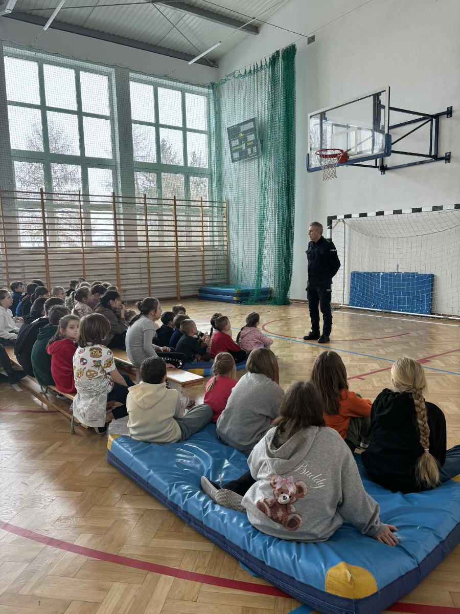 Policjant przekazuje społeczności szkolnej informacje na temat bezpieczeństwa podczas jazdy spacerów oraz ferii zimowych.