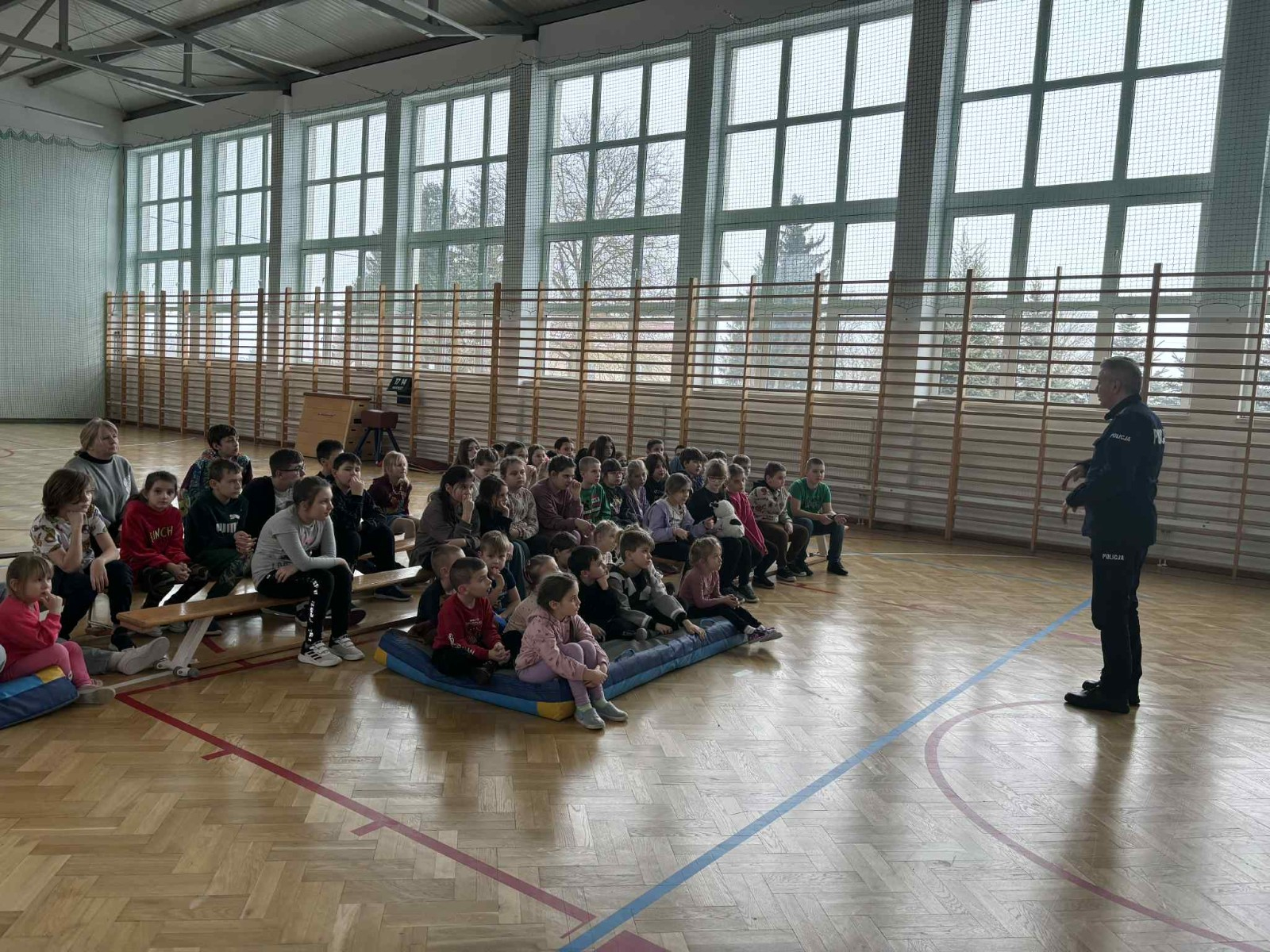 Policjant przekazuje społeczności szkolnej informacje na temat bezpieczeństwa podczas jazdy spacerów oraz ferii zimowych.