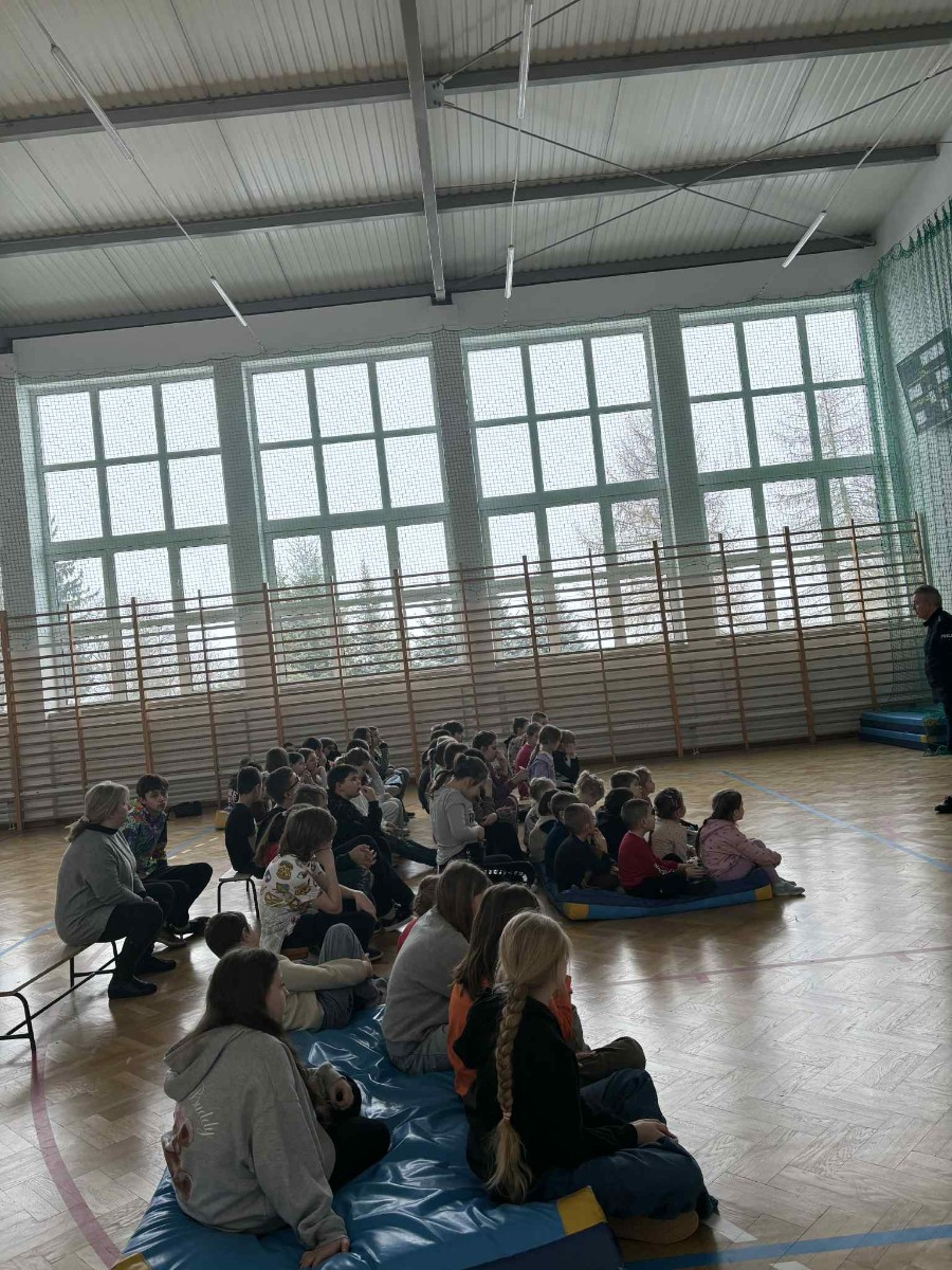 Policjant przekazuje społeczności szkolnej informacje na temat bezpieczeństwa podczas jazdy spacerów oraz ferii zimowych.