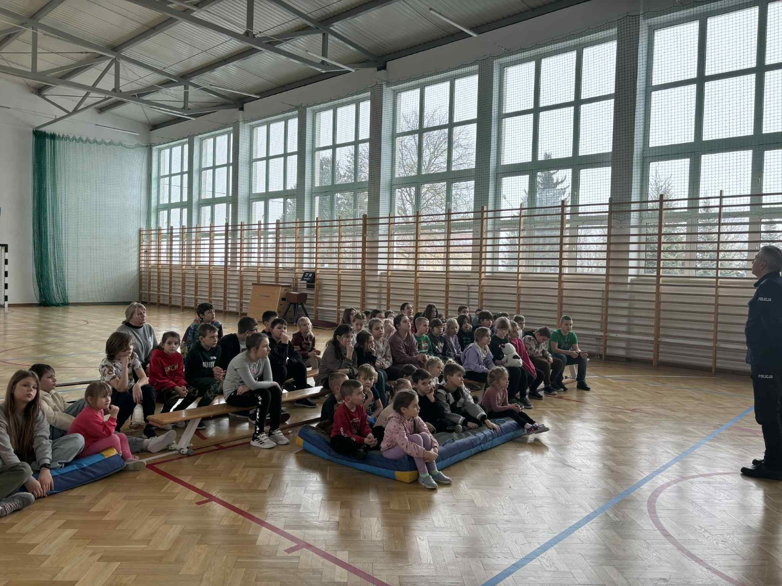 Policjant przekazuje społeczności szkolnej informacje na temat bezpieczeństwa podczas jazdy spacerów oraz ferii zimowych.