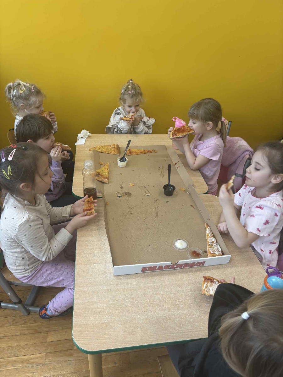 Dzieci degustują pizzę.