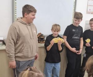 Uczniowie klasy szóstej i ósmej z uśmiechami wręczonymi przez młodszych kolegów