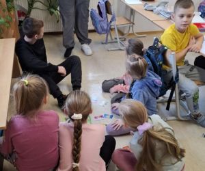 Zabawy integracyjne dla najmłodszych – uczniowie klasy pierwszej siedzą w kole ze starszymi uczniami