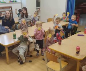 Przedszkolaki z uczniami klasy ósmej i szóstej z rysunkami uśmiechniętych buziek w dłoniach