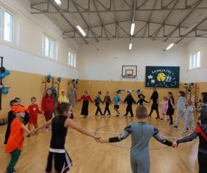  Dzieci  wraz z nauczycielami trzymające się za ręce i tańczące w kółeczku