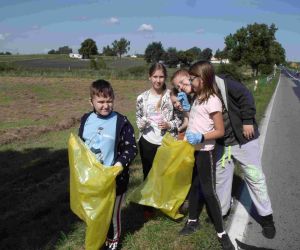 Czworo uczniów z workami na śmieci przy szosie