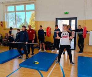 Jeden uczeń podnosi sztangę z obciążeniem, a drugi podnosi sztangę bez obciążenia