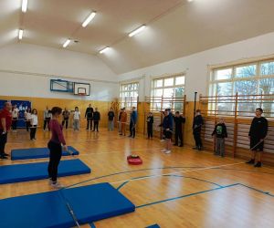 Uczniowie w sali gimnastycznej podczas treningu z drążkami