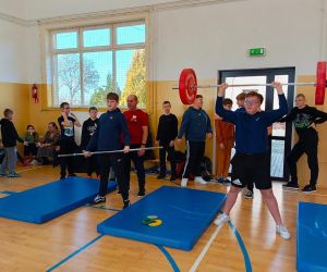 Jeden uczeń podnosi sztangę z obciążeniem, a drugi trzyma sztangę bez obciążenia