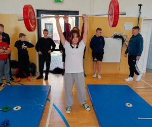 Uczennica podnosi sztangę z obciążeniem